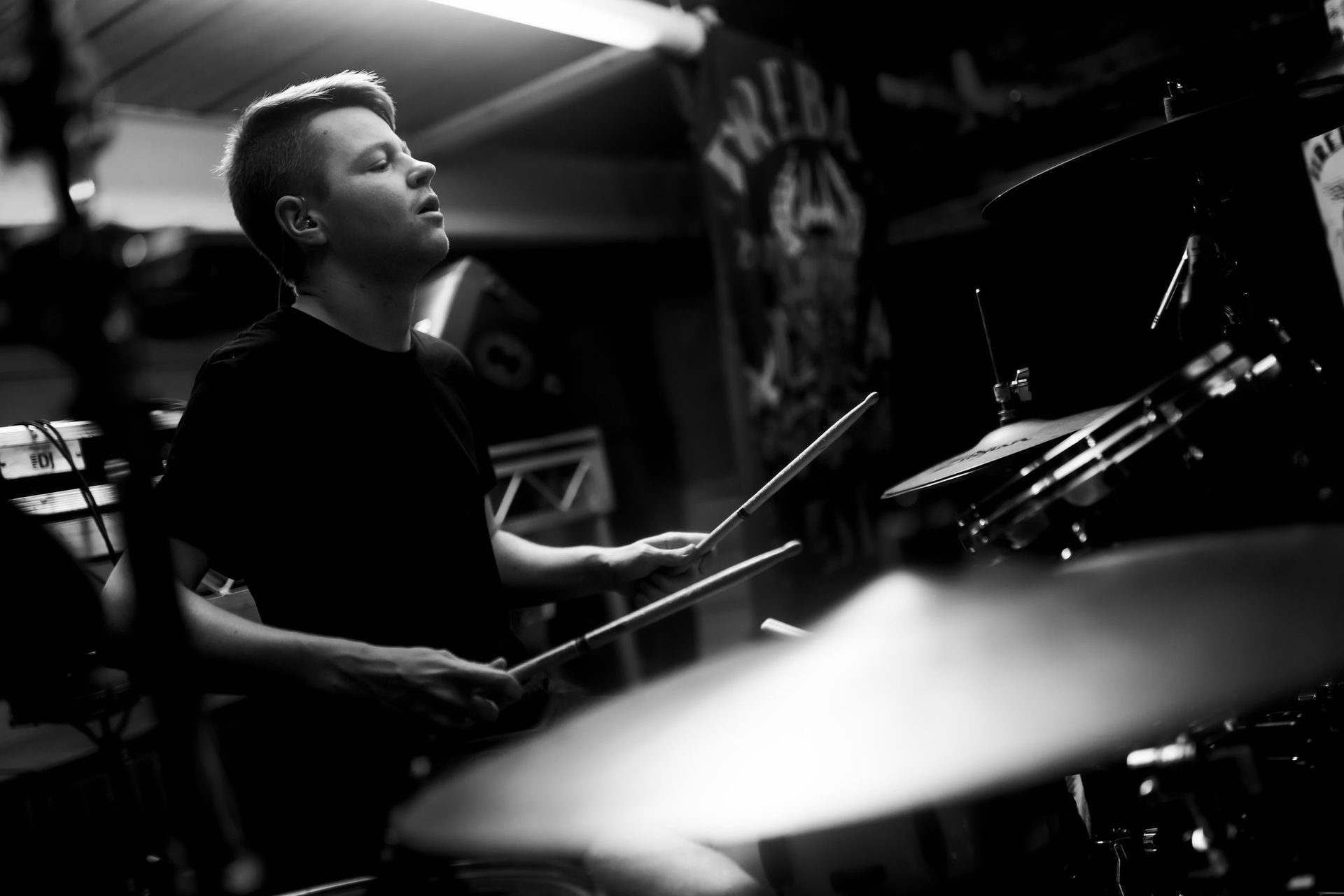 A young drummer in a dramatically lit studio